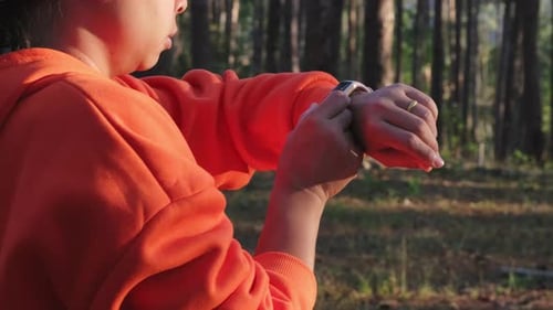 Young Adult Using Smart Watch in Forest