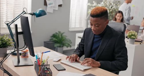 Elegant Man Working in an Office Boy is Sitting Behind Desk in Front of Computer Checking
