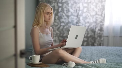 Woman Works on Laptop in Bed at Home