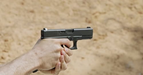 Movimiento lento de una pistola de mano disparando en un campo de tiro con el cartucho volando