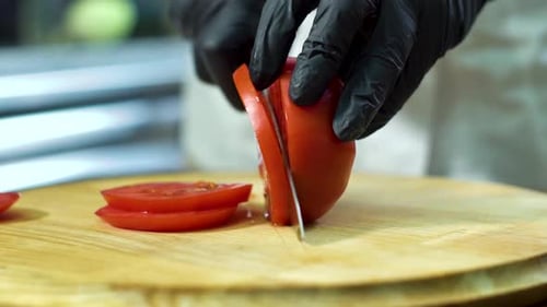 Chef Slicing Tomato on Wooden Cutting Board