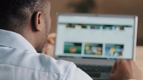 Vista por encima del hombro del hombre africano irreconocible joven diseñador web estadounidense programador