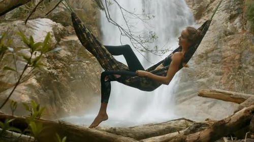 Woman Relaxing in Hammock Near Waterfall
