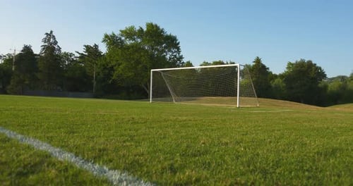 A wide, low angle dolly of an empty soccer field on a sunny, summer morning.