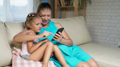 Woman and Child Using Mobile Phone on Couch