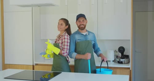 Smiling Couple Ready for Cleaning in Modern Kitchen