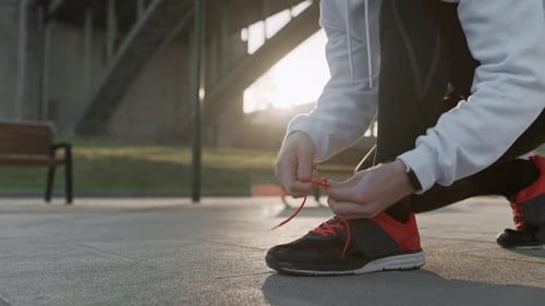Young Man Tying His Shoelaces Before Starting Daily Routine Workout. Man Doing Exercises and Warm Up