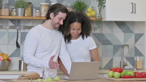 Couple in Kitchen Using Laptop Together