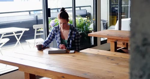 Caucasian businesswoman using digital tablet in cafeteria at office 4k