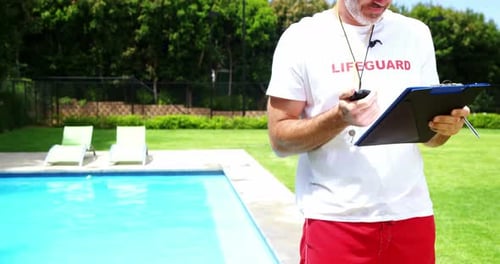 Lifeguard Stands By a Swimming Pool on Duty