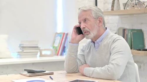 Man Talking on Phone at Desk Indoors