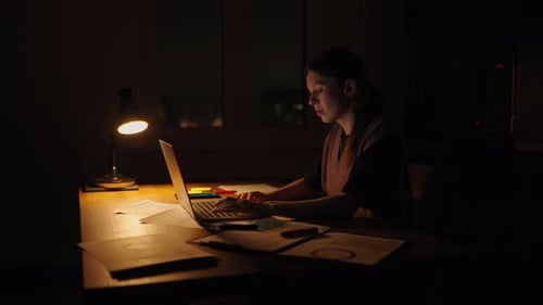 Young Adult Works on Laptop at Night