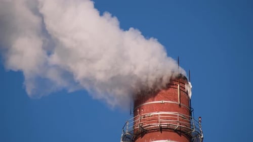 Industrial Smokestack Puffing Smoke into Blue Sky