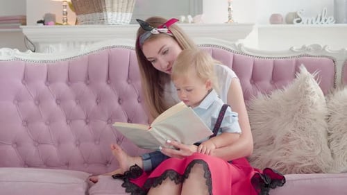 Woman Reading Book to Baby on Pink Couch
