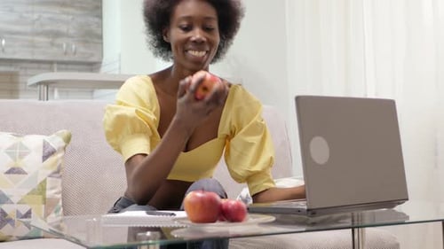 Woman Eating Apple While Working on Laptop