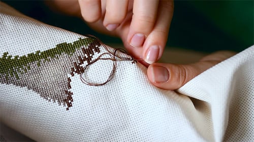 Close Up of Woman Cross Stitching Fabric Art