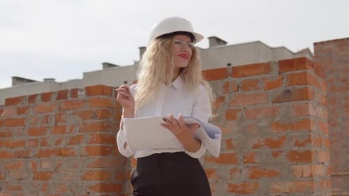 Architektin in Geschäftskleidung steht draußen auf der Baustelle