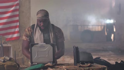 Black Military Man Using Laptop and Radio at Base