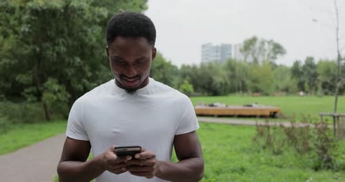 Young Man Using Mobile Phone in Green Park