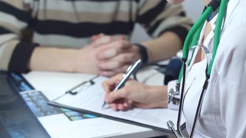 Doctor Taking Notes on Patient's Medical Chart