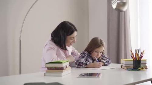 Woman Helping Girl with Homework at Table