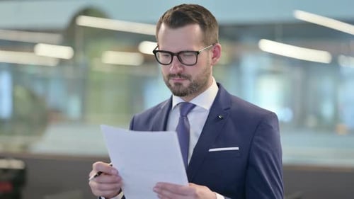 Man in Suit Reviews Documents in Office