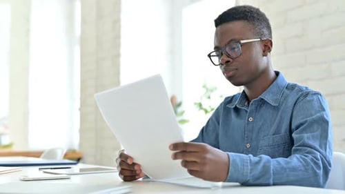 Upset Young African Man Having Loss on Documents in Office