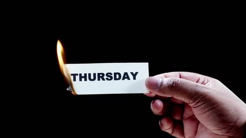 Hand Holds Burning 'Thursday' Card Close Up