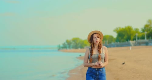 Pretty Young Woman Walking on the Sea with a Hat