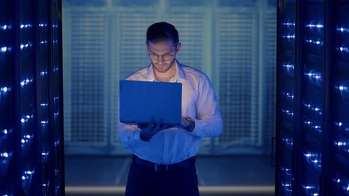 Man Uses Laptop in Data Center Server Room