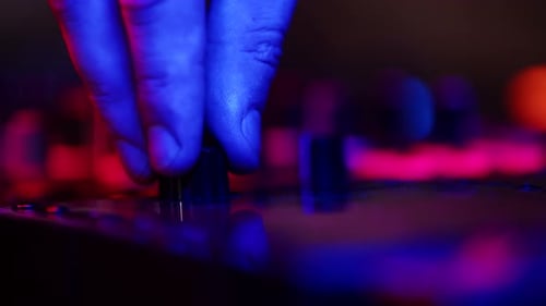 Hand Adjusting Sound Mixer in Neon Lighting