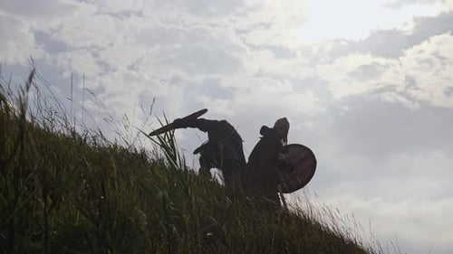 Silhouetted Figures in Medieval Battle on Grassy Hill