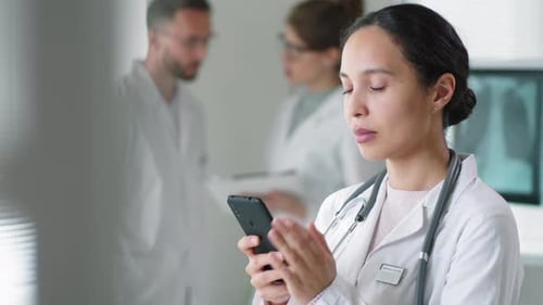 Female Doctor Uses Smartphone in Modern Hospital