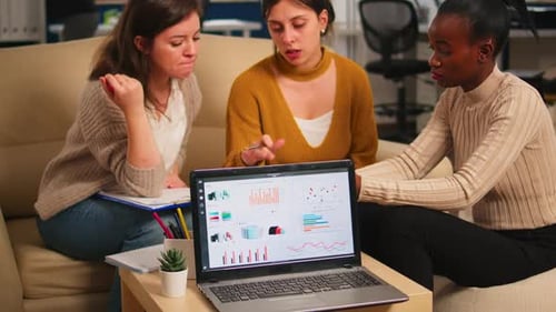 Women Collaborate on Data Analysis in Office