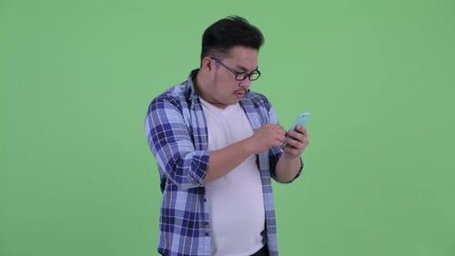 Man Celebrates Success with Smartphone on Green Screen