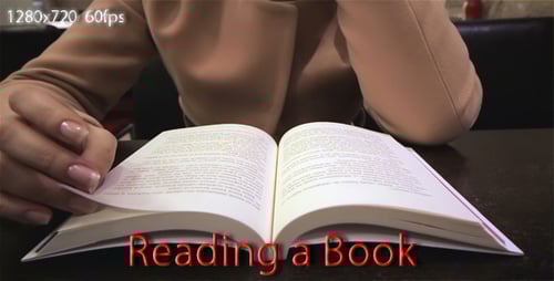 Woman reads a book indoors, turning pages