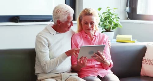 Elderly Couple Enjoys Tablet Together on Sofa