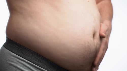 Manos de un hombre obeso tocando su gorda barriga