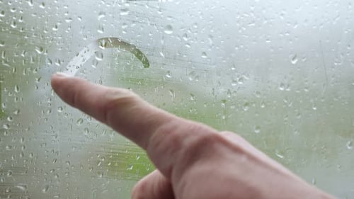 Finger Draws Heart on Rainy Window Close Up