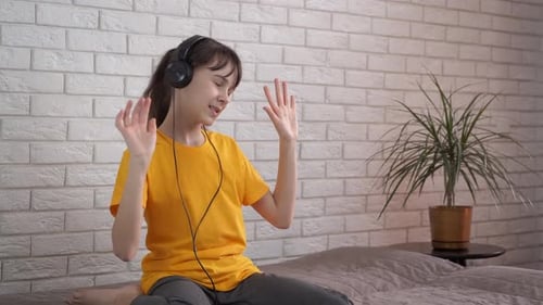 Teen Singing and Dancing with Headphones on Bed