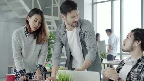 Business people discussing ideas in smart casual wear working on laptop at office