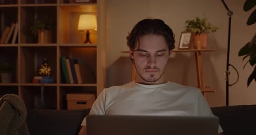 Crop View of Young Man Freelancer Using Laptop While Sitting on Couch at Home