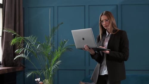 Confident Businesswoman Working on a Laptop in Her Modern Blue Modern Office Interior. Stylish