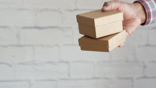 Hands Passing Stack of Cardboard Boxes
