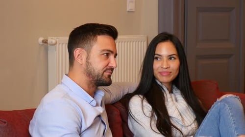 Man and Woman Talking on Red Sofa