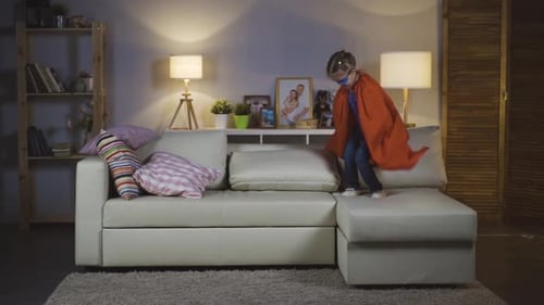 Girl in Superhero Costume Jumping on Couch