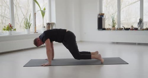 Man Practicing Yoga at Home on Yoga Mat