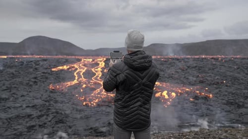 Photographer Controlling Drone And Looking Out Over Lava Field