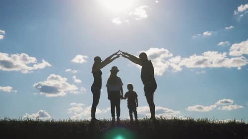 A Silhouette Happy Young Family at Sunset. Father, Mother and Two Children Building a House. Concept