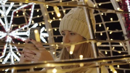 Woman Taking Photo of Christmas Lights at Night
